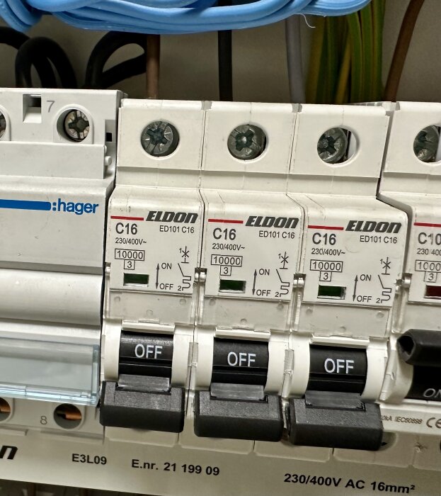 Tre C16 betjäningsbrytare från Eldon med svarta "OFF"-lägen synliga, installerade i elcentral, omgivna av blå och svarta kablar.