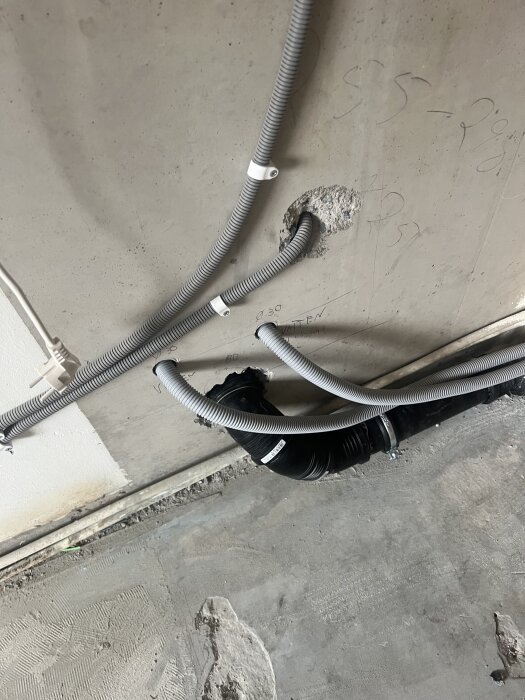 Installation av kabelrör och anslutning vid betongvägg med synliga kopplingspunkter.