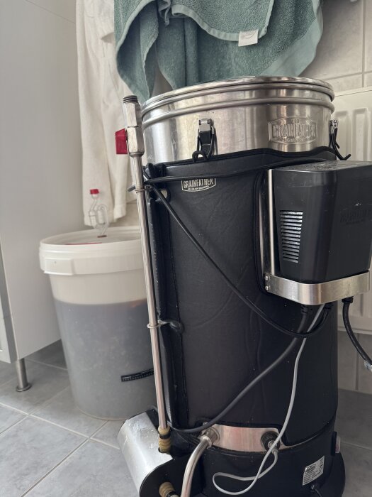 Bryggverk från Grainfather med jäshink i bakgrunden, används för hembryggning av öl.