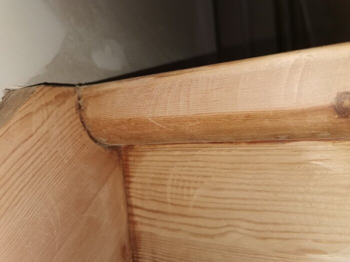 Översta trappsteget i trä sett från sidan, visar detaljer av trästruktur och anslutning till väggen.