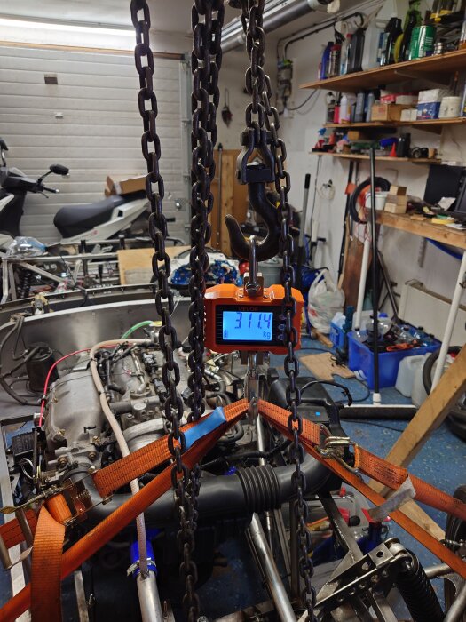 Vevlyft i garage lyfter bilens del för vägning, visar 311,4 kg på display.