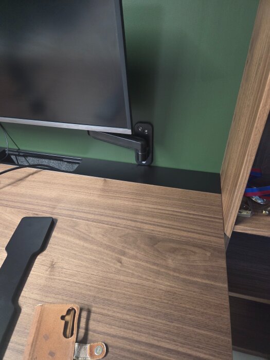 Skrivbord från Ikea med monitorarm nära monteringsväggen, visar exakt anpassning mellan väggfäste och skrivbordsyta.