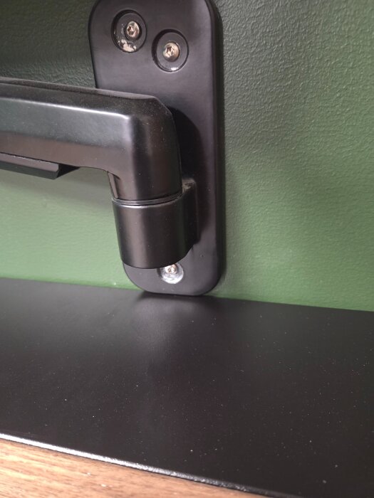 Väggfäste monterat precis ovanför ett svart skrivbord från Ikea, med exakt passform utan mellanrum.