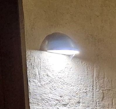 En ytterlampa som lyser direkt nedåt, monterad på en vägg, belyser trappsteg och entré.