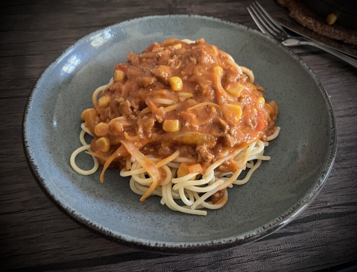 Spaghetti med köttfärssås i mexikansk stil, serverad på en grå tallrik.