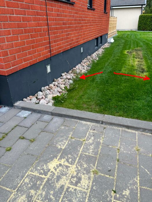 Bild av en husfasad med stenkross intill grunden och en gräsmatta med pilar som indikerar lutning.