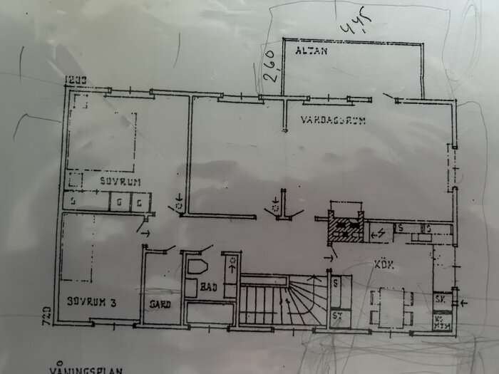 Planritning av bottenvåningen med markeringar för utbyggnad vid altanen, vardagsrum och kök. Visar rumsplacering och befintliga möbler.