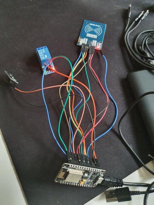Elektronisk krets med ESP8266, RFID-läsare och relä ihopkopplade med kablar för hemlig dörröppning i källarprojekt.