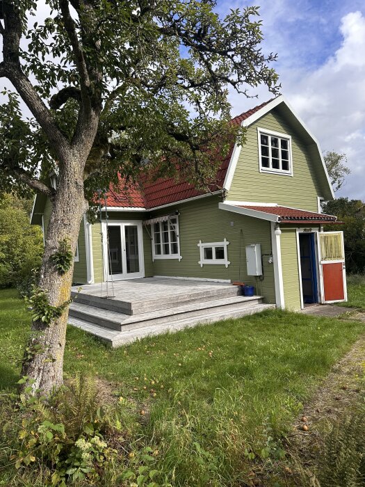 Fritidshus på Gotland med träfasad och rött tak omgivet av träd och gräs. Planerar att isolera vinden och åtgärda glipor mellan plankor.
