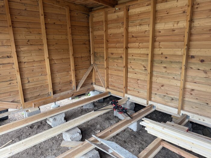 Inuti en bod under renovering med förstärkta väggar och golv, där nya plintar och reglar har installerats.