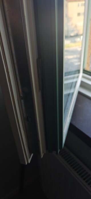 Äldre tvåglasfönster med extra glas monterat, delvis öppet, visar karmens och fönstrets delar samt potentiell plats för fönsterspaltventil.