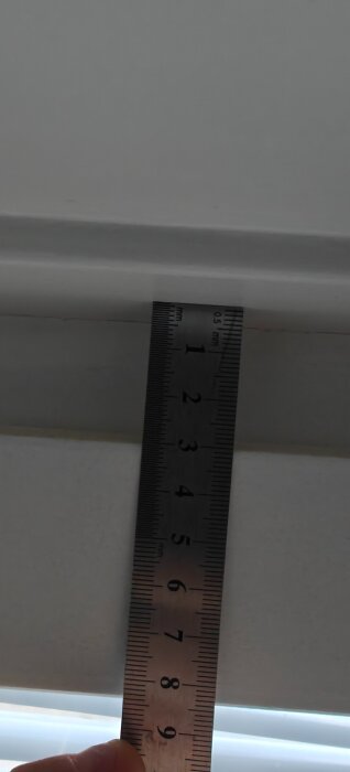 Linjal mäter avstånd mellan fönsterkarm och ram, visar cirka 1,5 centimeter.