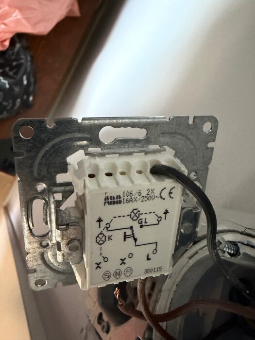 Elektrisk brytare med tre trådar inkopplade, vit bakgrund med symboler och text, svart tråd markerad som fas.
