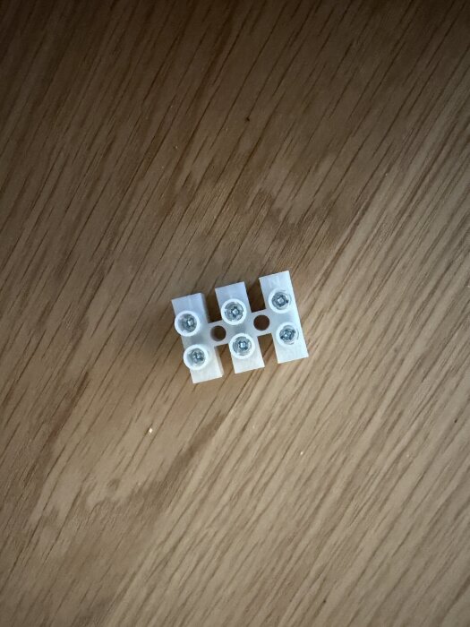Vita elektriska kopplingsplintar för kabelanslutning, placerade på en träyta.