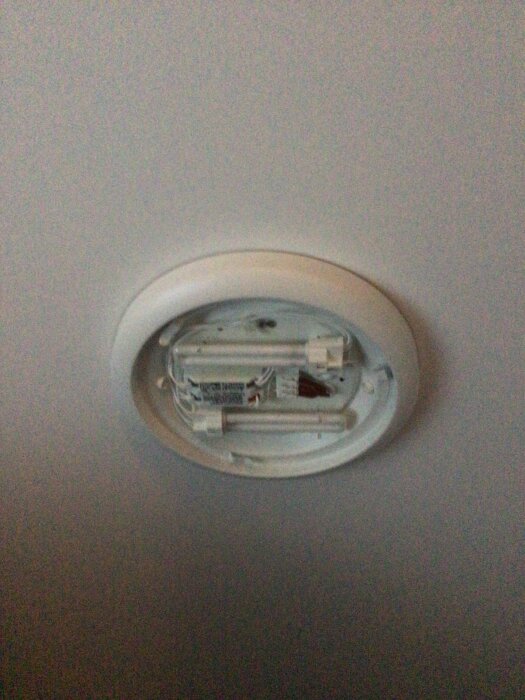 Taklampa monterad i tak med synliga elkablar och anslutningar, utan glödlampa eller lampskärm.