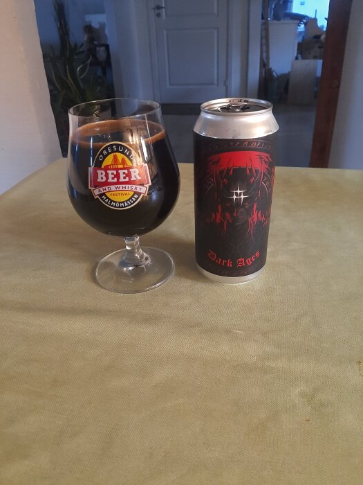 Ett glas och en burk med ölet "Dark Ages" står på ett bord, genomskinlig kupa med logo från Beer and Whisky Festival.