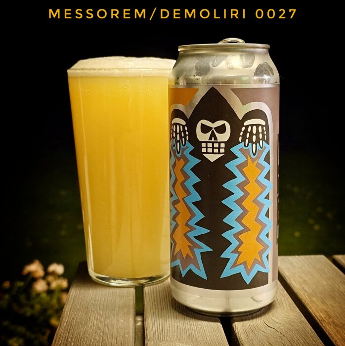 Ett glas med skummande, gyllengul dryck bredvid en burk med färgglad dödskalle-design på en träterrass.