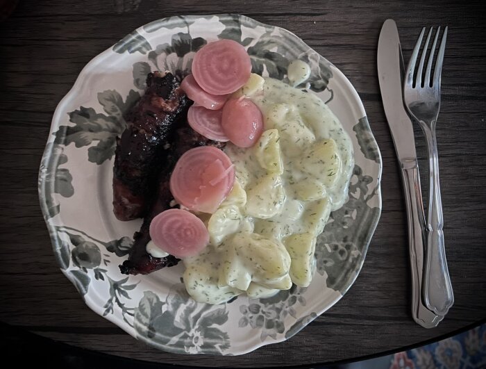 Tallrik med isterband, dillstuvad potatis och inlagda rödbetor, serverad med bestick på bordet.
