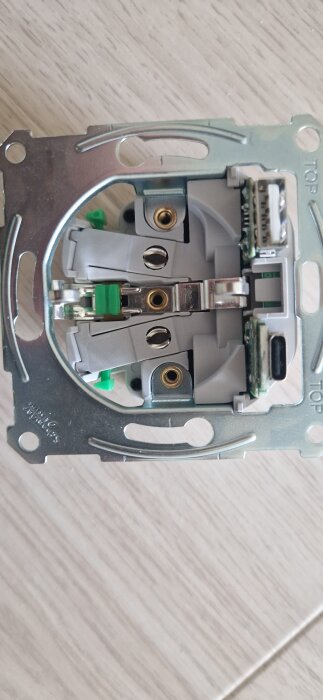 Vägguttag med USB-ingångar och snabbkopplingar, med gröna spakar, visas framför vit bakgrund, redo för montering.
