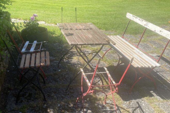 Bild av en renoverad möbelgrupp från 1896 med träbord, bryggeristolar och en trädgårdssoffa, placerade utomhus på en stenlagd yta.