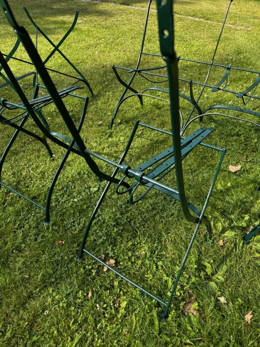 Gröna stålunderreden till trädgårdsstolar av märket Wedevåg, placerade på en gräsmatta under renoveringsprojekt.