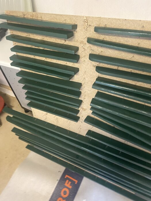 Målade gröna träbrädor torkar liggande på en yta i samband med renovering av möbler.