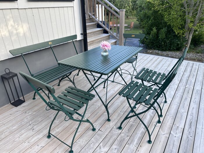 Renoverade trädgårdsmöbler från 1896 i mörkgrönt, bestående av bord, stolar och soffa, målade med linoljefärg, placerade på en altan.