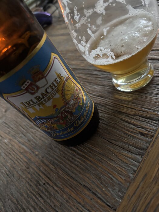 Flaska med oktoberöl från Irlbacher bredvid ett halvdrucket glas på ett träbord.