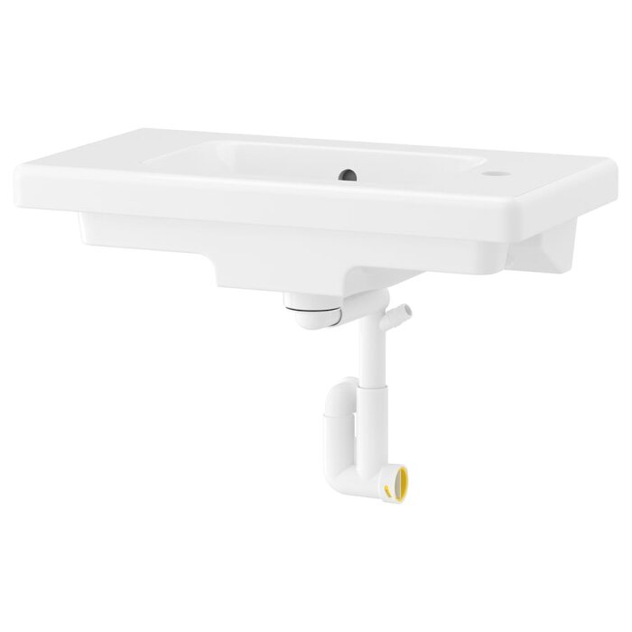 Kompakt vattenlås under ett vitt tvättställ, med fokus på platsbesparande design för badrumskommod.