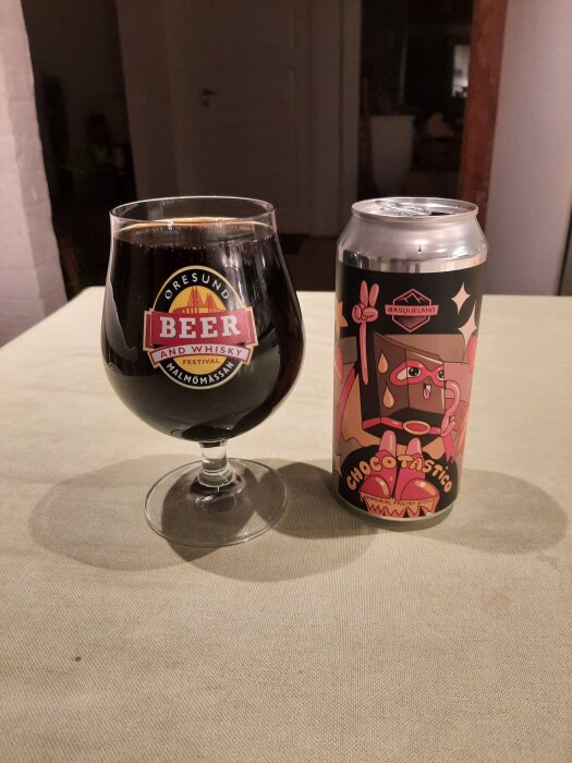 Ölglas med mörk öl och ölburk med etikett "Chocotastic" på ett bord.