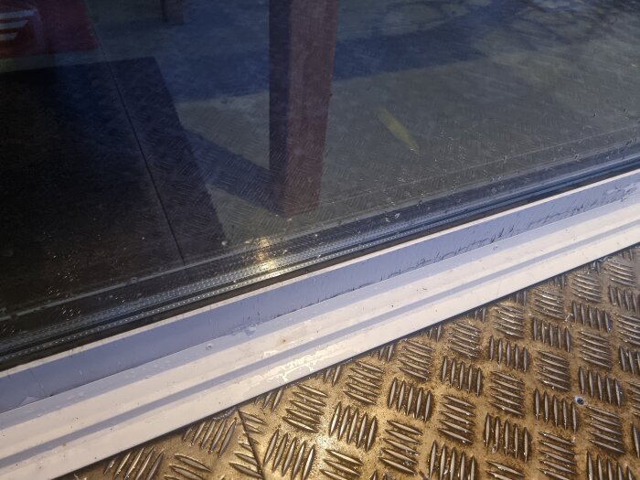 Närbild av fönsterparti i tillbyggnad, visar vattenläckage mellan karm och båge under ett slagregn.