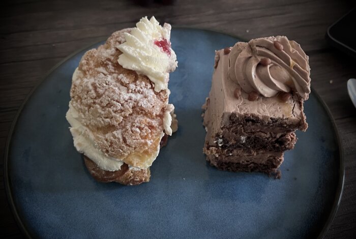 Två bakelser på ett fat: en Mariabakelse med grädde och sylt samt en chokladbakelse med smörkräm och daimkulor.