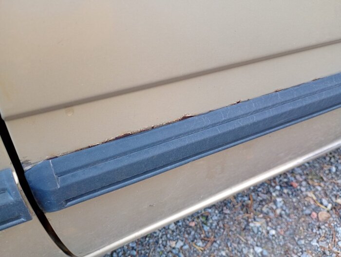 Rostfläckar vid dörrlisten på en beige Volvo-bil, där plastlisten möter plåten.