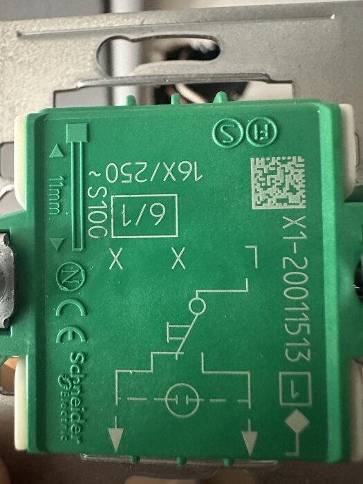 Närbild av baksidan på en Schneider Electric brytare, visar anslutningar märkta L och X, samt elektriska symboler och specifikationer.