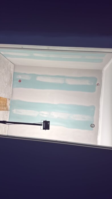 Nymålade och gipsade väggar i ett renoveringsprojekt, med en lampa och några verktyg på golvet.