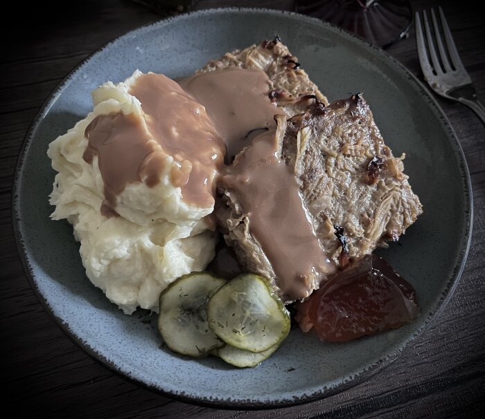 Tallrik med kålpudding, potatismos med sås, inlagd gurka och äppelgelé.