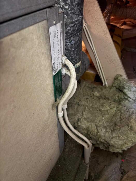Två grova elkablar som går in i en metallpanel bredvid en ventilationsrör, en fråga ställs om funktionen för kabel nummer två.