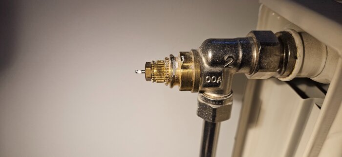 Närbild av en termostatventil på ett element, där den justerbara sifferringen saknas.