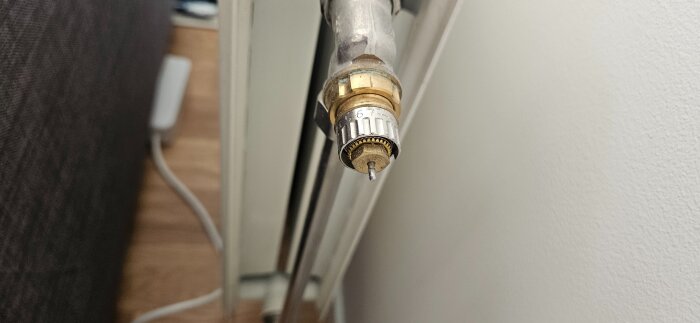 Närbild av en termostatventil på ett vattenburet element. Ventilen saknar justeringsring för inställning av vattenflöde.