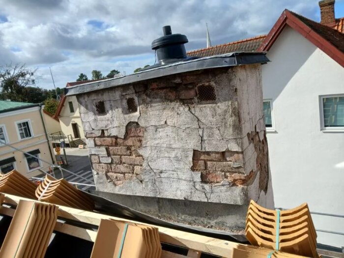 Gamla tegelstenar och sprickor på en skorsten som inte används för eldning, synlig från ett tak under renovering.