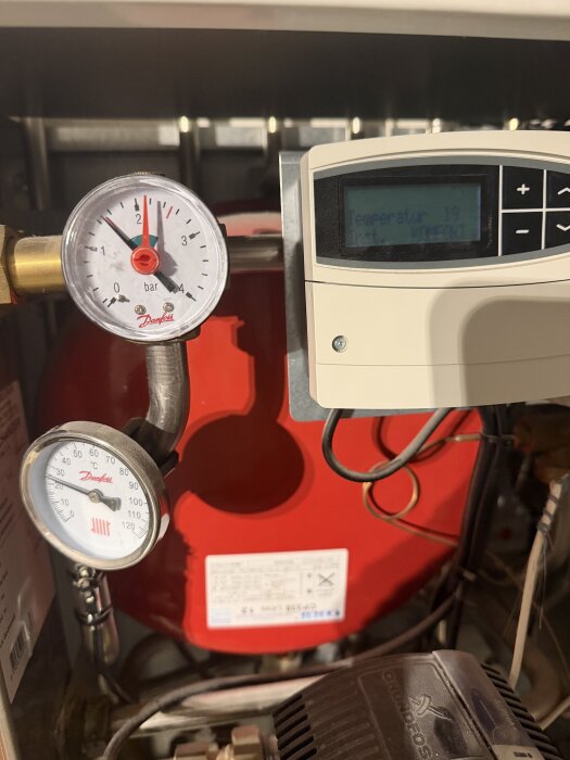 Bild av en värmeanläggning med Danfoss-reglering, där tryckmätaren visar 1,6 bar och en termometer visar 25 °C.