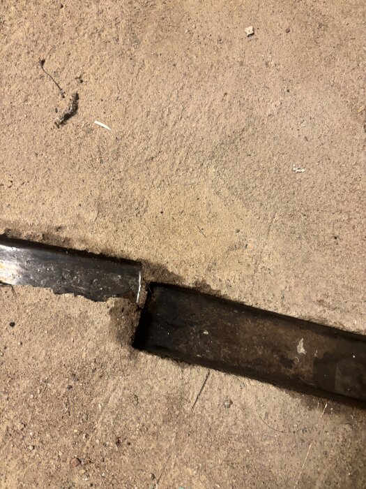 Spricka i fuktigt betonggolv i källare med synliga fogar och mörk missfärgning, troligtvis orsakad av vatteninträngning.