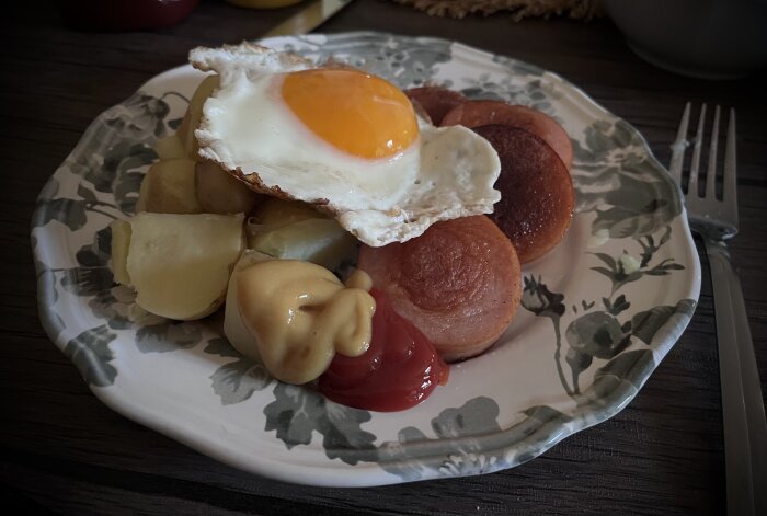 Stekt falukorv med hemodlad kokt potatis, ketchup, senap och ett stekt ägg med gulan uppåt på en tallrik.