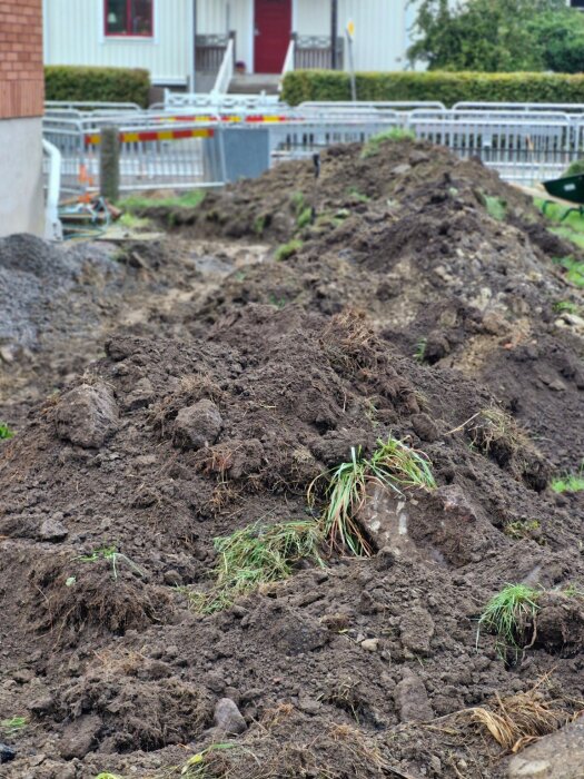 Hög av jord och fyllnadsmassor i en trädgård, troligtvis uppgrävd vid anläggning av gång eller parkering.