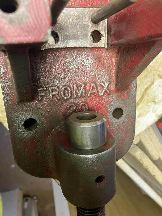Röd metallyta med texten "FORMAX 20", visar kugghjul eller rulle, del av maskin eller verktyg, rengjord och fotograferad i närbild.