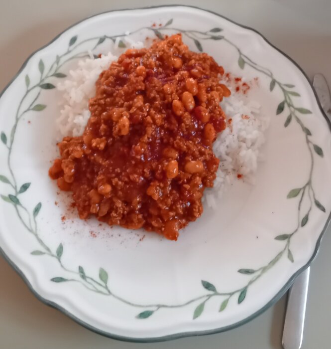 Tallrik med serverad chili con carne ovanpå ris.