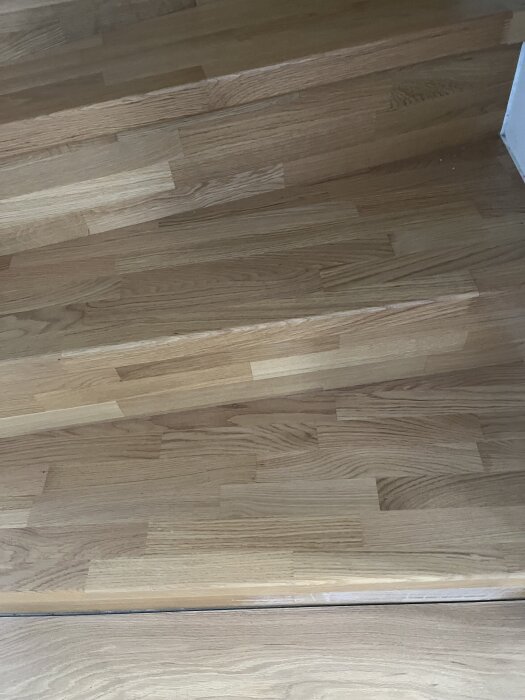 Trätrappa med mönstrad yta i olika nyanser av brunt, redo för slipning och behandling med hårdvaxolja för förbättrad halksäkring och estetik.
