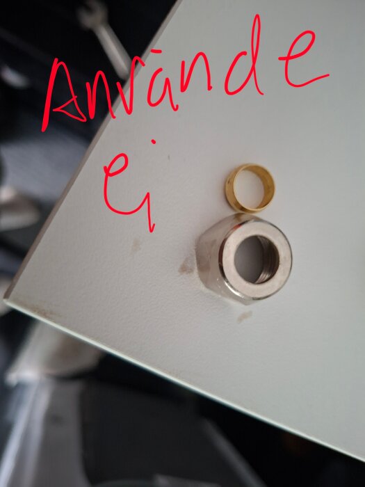 Mutter och ring på skiva med texten "Använde ej" skrivet ovanpå.