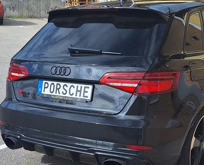 Bakdelen av en svart Audi RS3 med registreringsskylten "PORSCHE".