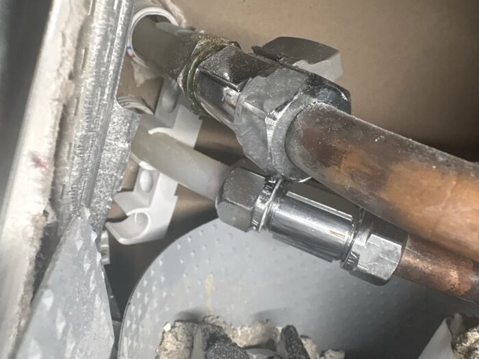 Vattenanslutning med rör-i-rör-system (PEX) och kopplingar som sticker ut från väggen, kopplad till en avstängningsventil med kopparrör.